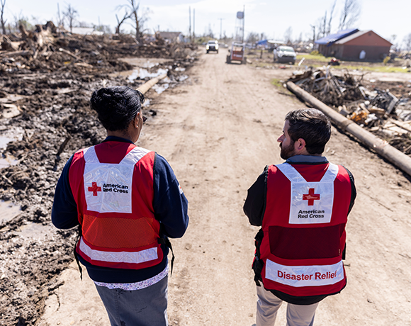 Red Crossers Charlene Walker and Eric Besson walk down a street on Wednesday in Silver City, Miss. The town of 217 people was heavily damaged by a tornado Friday. Clean-up has already begun, debris piles sitting next to the streets., Many residents gathered at their homes on Wednesday as Walker went door-to-door to tell residents who were cleaning up about resources available at the Red Cross Community Hub, based at the neighborhood church. As many as 2,000 homes across Mississippi sustained major damage or have been destroyed, according to early estimates. More than 330 trained Red Cross disaster workers are on the ground to work with partners in making sure everyone has a place to stay, meals, emotional support and comfort.